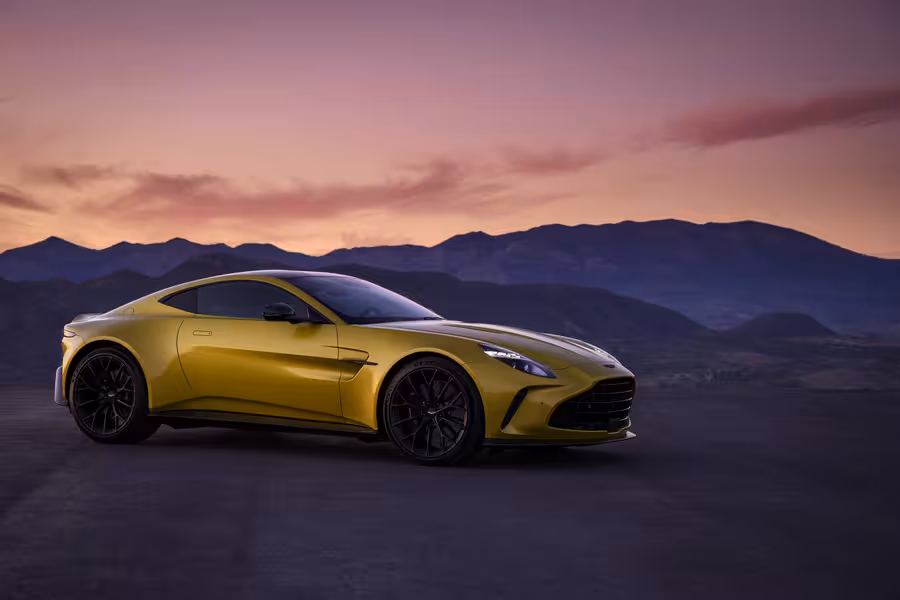 Žlutý současný Aston Martin Vantage v tříčtvrtečním pohledu za soumraku