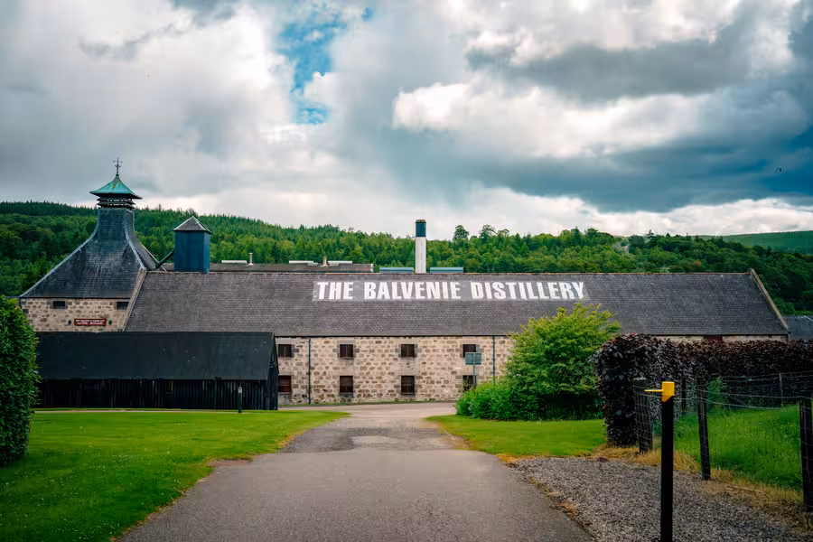Historická budova palírny The Balvenie obklopená zelení