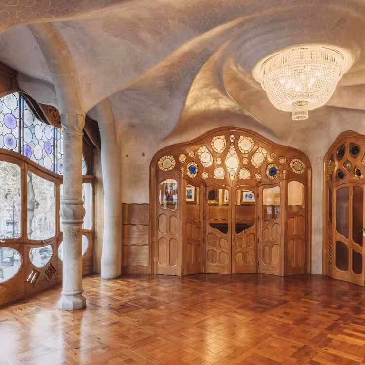 Hlavní salon Casa Batlló s dřevěnými dveřmi, barevným sklem a zvlněným stropem