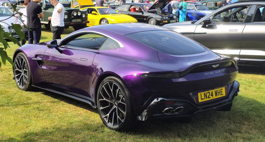 Moderní Aston Martin Vantage V8 v tmavém laku fotografovaný z boku a zepředu