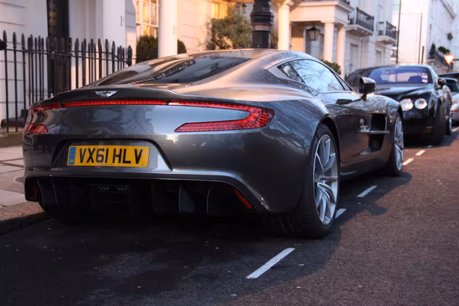 Stříbrný Aston Martin One-77 vystavený v interiéru automobilové přehlídky