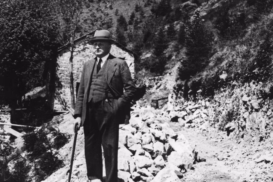 Ermenegildo Zegna stojí v obleku a klobouku na kamenité trase horské silnice