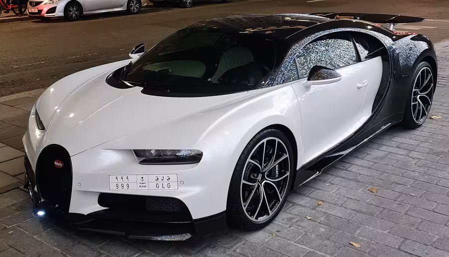 Bílé Bugatti Chiron s černou střechou, lesklými detaily a zadním křídlem zaparkované v noci v Londýně