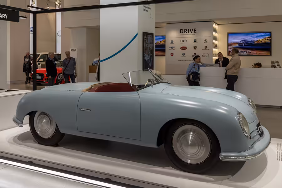 Světle modré Porsche 356 No. 1 Roadster s červeným interiérem vystavené z boku v berlínském Volkswagen Group Forum