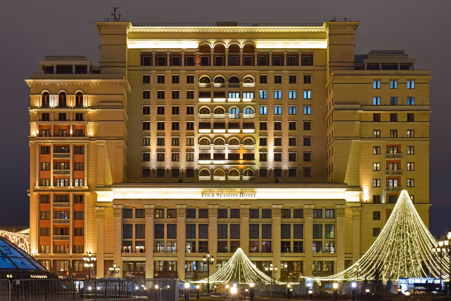 Noční průčelí hotelu Four Seasons Moscow se slavnostně osvětlenými stromy