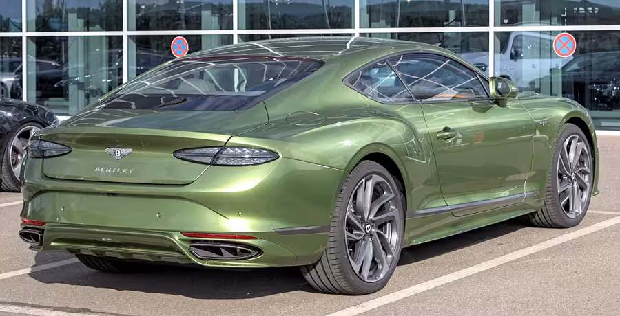 Zelený Bentley Continental GT čtvrté generace fotografovaný zezadu z pravé strany na venkovní automobilové akci