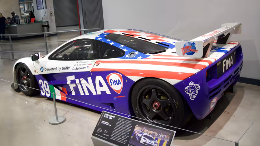 McLaren F1 GTR s číslem 39 v bílé, modré a červené livreji FINA vystavený v muzeu zezadu z levé strany
