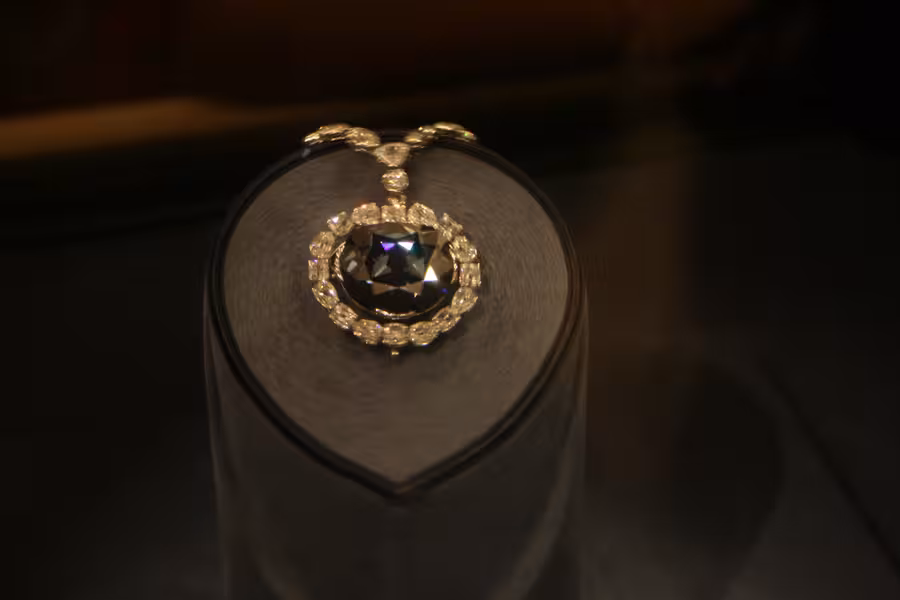 Tmavě modrý Hope Diamond obklopený bílými diamanty v náhrdelníku na muzejním podstavci