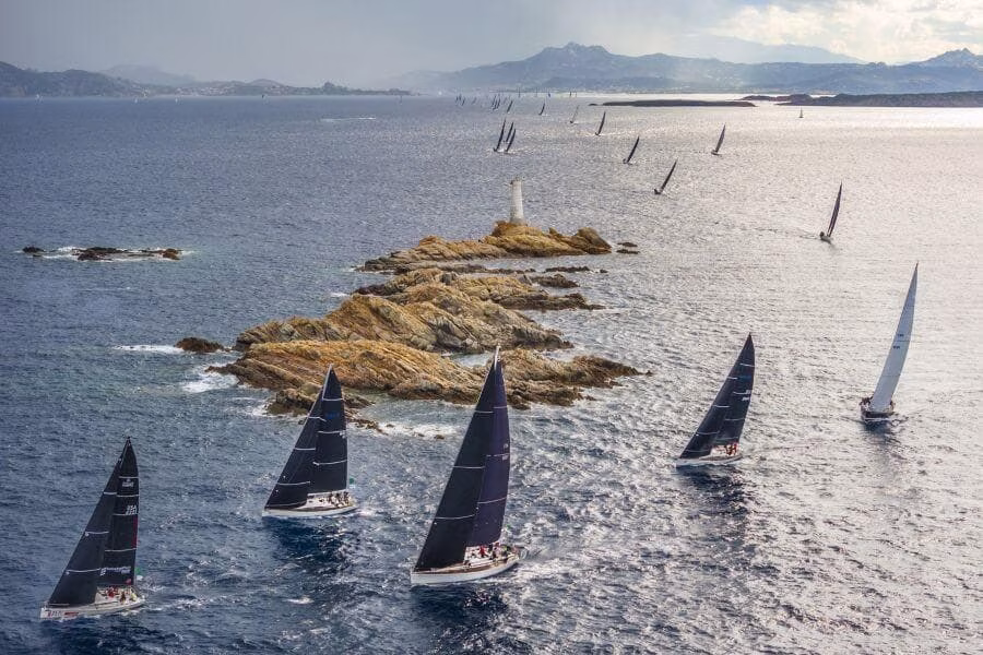 Závodní plachetnice Swan plují kolem majáku u Porto Cervo